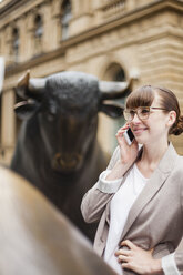 Deutschland, Hessen, Frankfurt, lächelnde Geschäftsfrau beim Telefonieren mit Smartphone vor der Börse - FMKYF000565