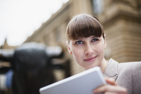 Deutschland, Hessen, Frankfurt, Porträt einer lächelnden Geschäftsfrau mit digitalem Tablet vor einem Börsenplatz, lizenzfreies Stockfoto