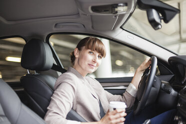 Germany, Hesse, Frankfurt, portrait of smiling businesswoman with coffee to go sitting in her car - FMKYF000574