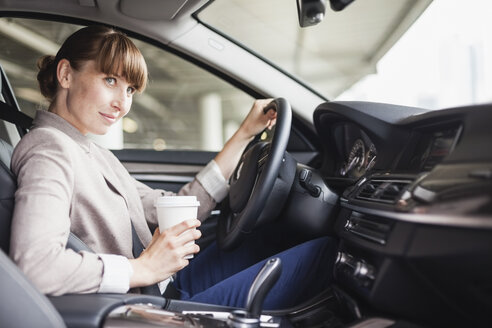 Germany, Hesse, Frankfurt, portrait of smiling businesswoman driving car with coffee to go in one hand - FMKYF000575