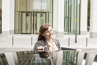 Deutschland, Hessen, Frankfurt, Porträt einer lächelnden Geschäftsfrau, die sich auf ihr Auto stützt - FMKYF000578