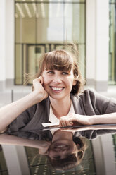 Deutschland, Hessen, Frankfurt, Porträt einer lächelnden Geschäftsfrau, die sich auf ein Autodach stützt - FMKYF000580