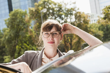 Porträt einer Geschäftsfrau, die sich auf ihr Auto stützt - FMKYF000600