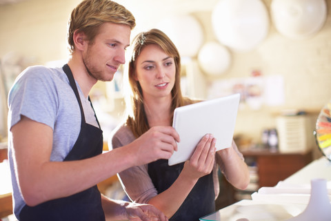 Ehepaar in einer Werkstatt mit digitalem Tablet, lizenzfreies Stockfoto