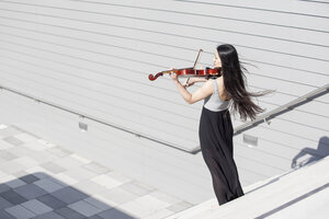 Young female Asian playing violin on stairs - MAD000013