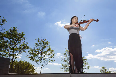 Junge Asiatin spielt Geige vor dem Himmel - MAD000025