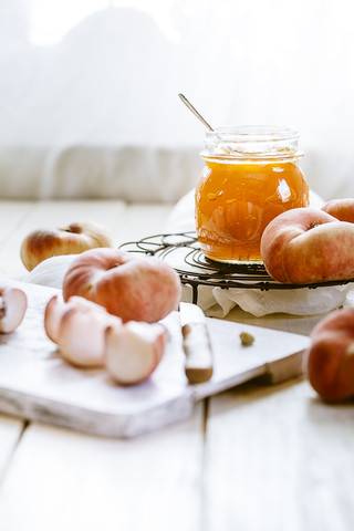 Geschnittene und ganze Donut-Pfirsiche und ein Glas Pfirsichmarmelade, lizenzfreies Stockfoto