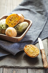 Hölzerne Schale mit Kaktusfeigen auf Stoff und Schiefer - SBDF001246