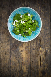 Bowl of lamb's lettuce, Valerianella locusta, with goat cream cheese on wood - LVF001932