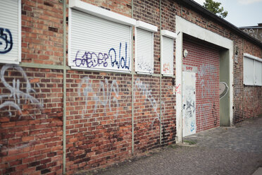 Deutschland, Sachsen, Leipzig, Graffiti an Fassade und geschlossenen Rollläden eines alten Industriegebäudes - DWF000178