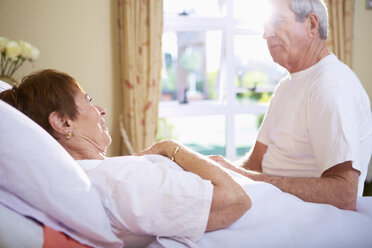Senior woman lying in hospital bed talking to senior man - ZEF000945