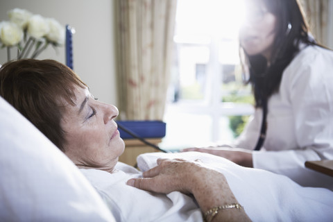 Ältere Frau im Krankenhausbett liegend, lizenzfreies Stockfoto