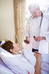 Arzt im Gespräch mit einer älteren Frau im Krankenhausbett - ZEF000953