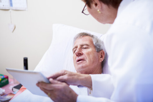 Arzt zeigt einem älteren Mann im Krankenhausbett ein digitales Tablet - ZEF000962