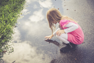 Kleines Mädchen spielt mit Wasser in einer Pfütze - SARF000860