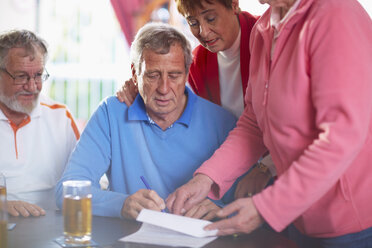 Senior man with friends signing document - ZEF001025