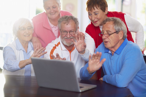 Ältere Freunde halten eine Videokonferenz am Laptop ab, lizenzfreies Stockfoto