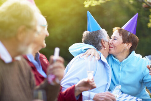 Ältere Freunde umarmen sich auf einer Gartenparty zum Geburtstag - ZEF001031