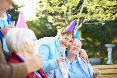 Ältere Freunde umarmen sich auf einer Gartenparty zum Geburtstag - ZEF001034