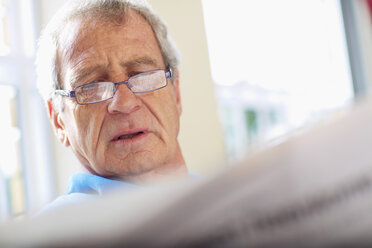 Senior man reading newspaper at home - ZEF001045