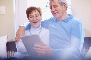 Glückliches Seniorenpaar nutzt digitales Tablet zu Hause - ZEF001057