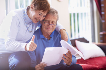 Happy senior couple reading document at home - ZEF001061