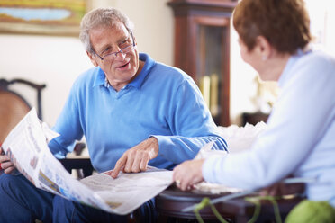 Senior man with newspaper at home talking to wife - ZEF001065