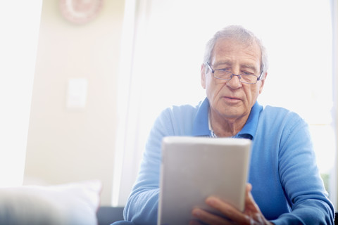 Älterer Mann benutzt digitales Tablet zu Hause, lizenzfreies Stockfoto