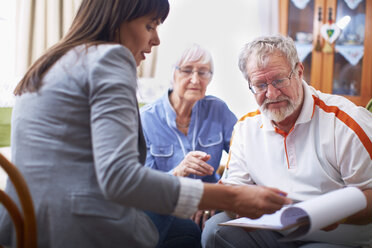 Woman explaining document to senior couple - ZEF001084