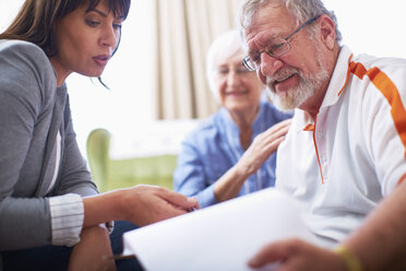 Woman explaining document to senior couple - ZEF001086