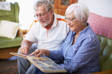 Senior couple at home looking at photo album - ZEF001089