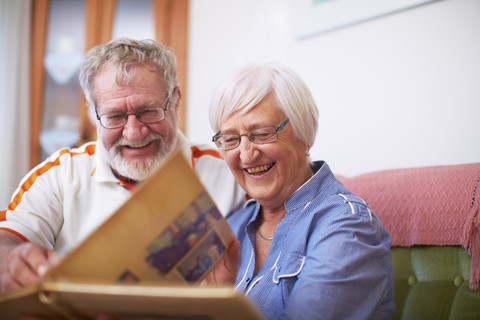Älteres Paar zu Hause beim Betrachten eines Fotoalbums, lizenzfreies Stockfoto
