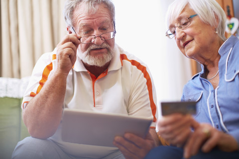 Älteres Paar kauft zu Hause online ein, lizenzfreies Stockfoto