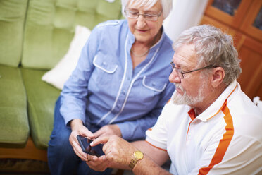 Senior couple with smart phone at home - ZEF001094