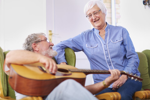 Älterer Mann mit Frau zu Hause beim Gitarrenspiel, lizenzfreies Stockfoto