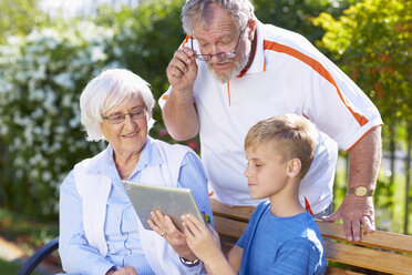 Grandson and grandparents using digital tablet in park - ZEF001117