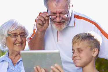 Grandson and grandparents using digital tablet - ZEF001118