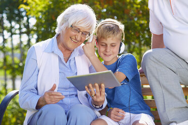Enkel und Großeltern nutzen ein digitales Tablet im Park - ZEF001119
