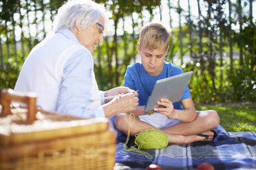 Enkel mit Digital-Tablet und Großmutter auf Picknick-Decke - ZEF001123