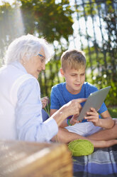 Enkel mit Digital-Tablet und Großmutter auf Picknick-Decke - ZEF001124
