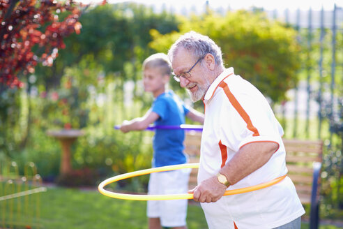 Großeltern mit Enkel im Park beim Üben mit Hula-Hoop-Reifen - ZEF001144