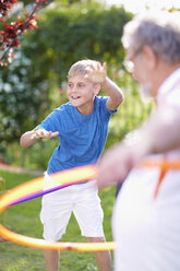 Grandparents with grandson in park practising with hula hoops - ZEF001145