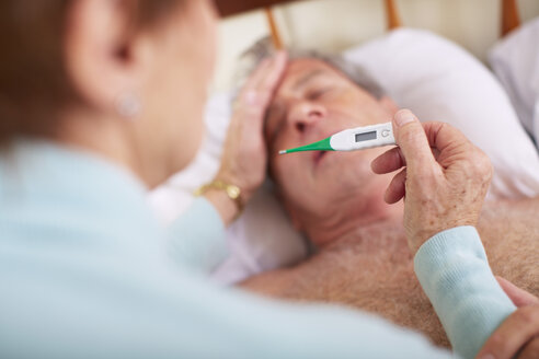 Ältere Frau misst die Temperatur ihres kranken Mannes zu Hause - ZEF001153