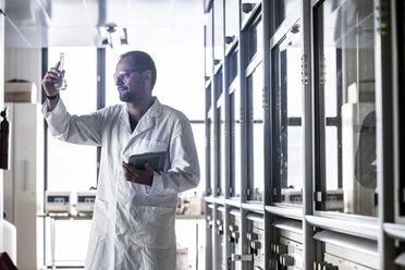 Chemist with Erlenmeyer flask controlling chemical test in a laboratory - SGF000863