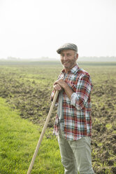 Smiling farmer standing in front of a field - UUF002017