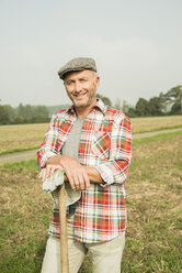 Porträt eines lächelnden Landwirts, der vor einem Feld steht - UUF002024