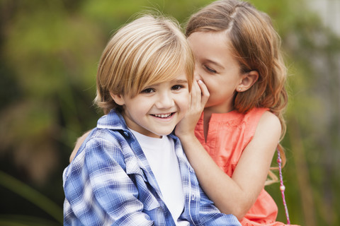 Mädchen flüstert einem Jungen ins Ohr, lizenzfreies Stockfoto