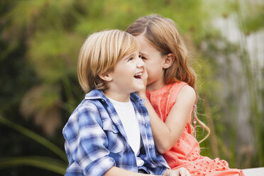 Girl whispering into boy's ear - WESTF020098