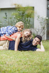 Glücklicher Vater, Tochter und Sohn liegen im Gras - WESTF020115