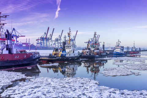 Deutschland, Hamburg, Schlepper auf der vereisten Elbe bei Sonnenaufgang, lizenzfreies Stockfoto